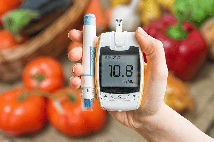 A hand holding glucometer and a healthy diet for diabetes in the background