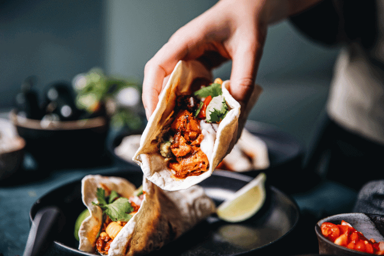 Close-up of a woman serving vegan tacos