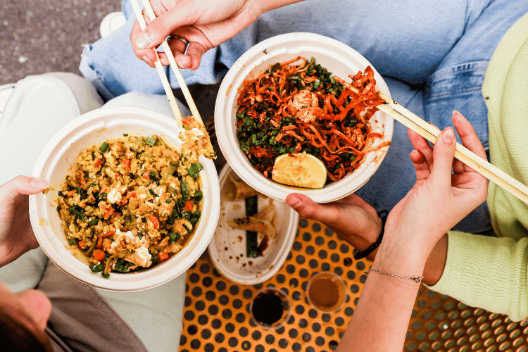 Top view of two persons eating Vegetarian meals in white bowls